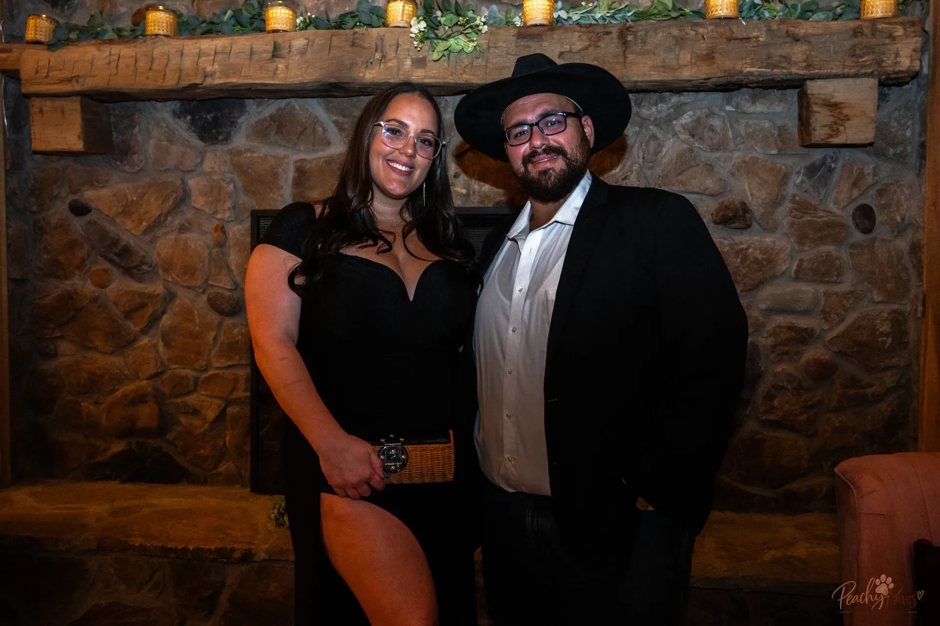 Gala guests posing together beside the rustic stone fireplace