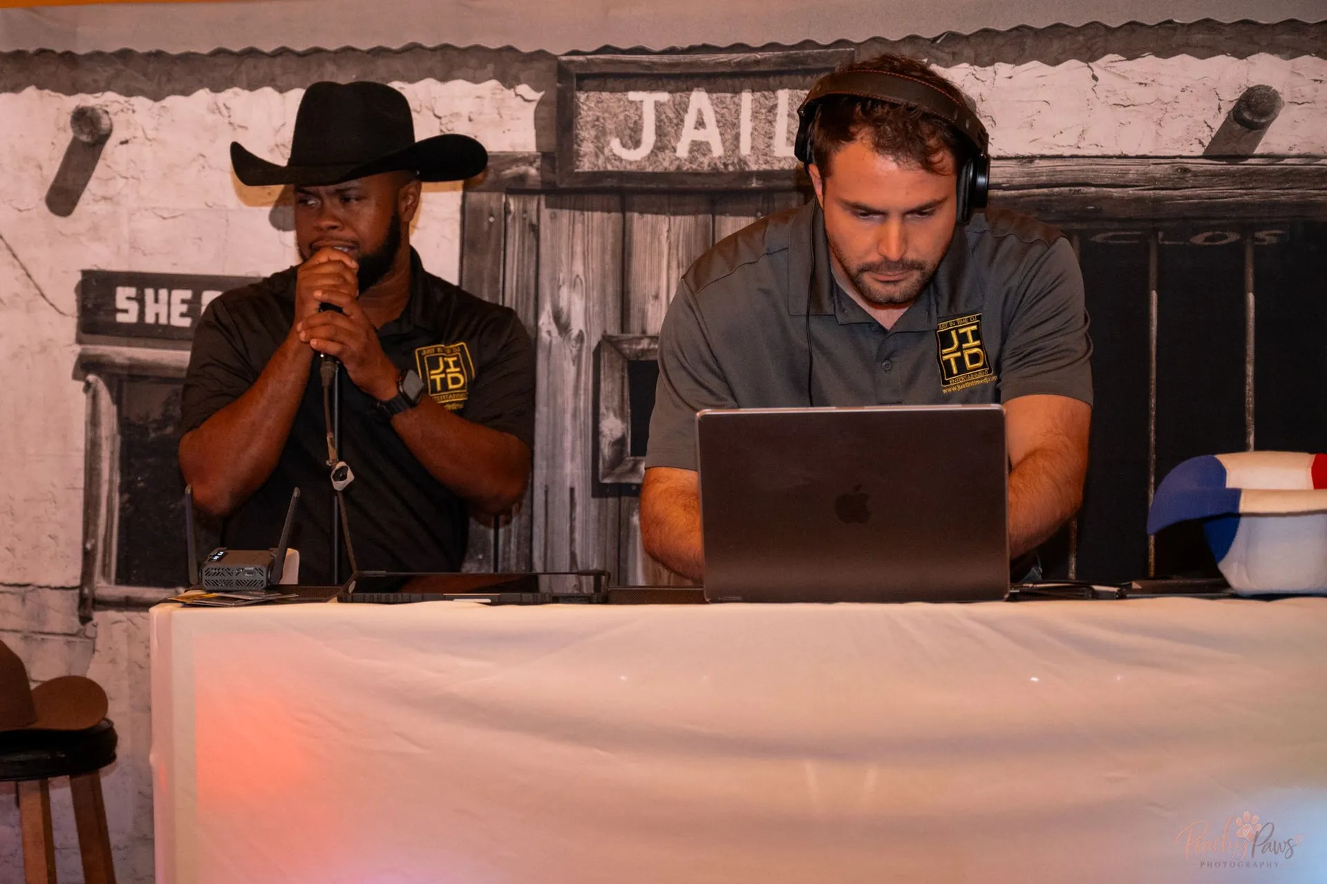 The event emcee and DJ working together beside the western-themed jail backdrop