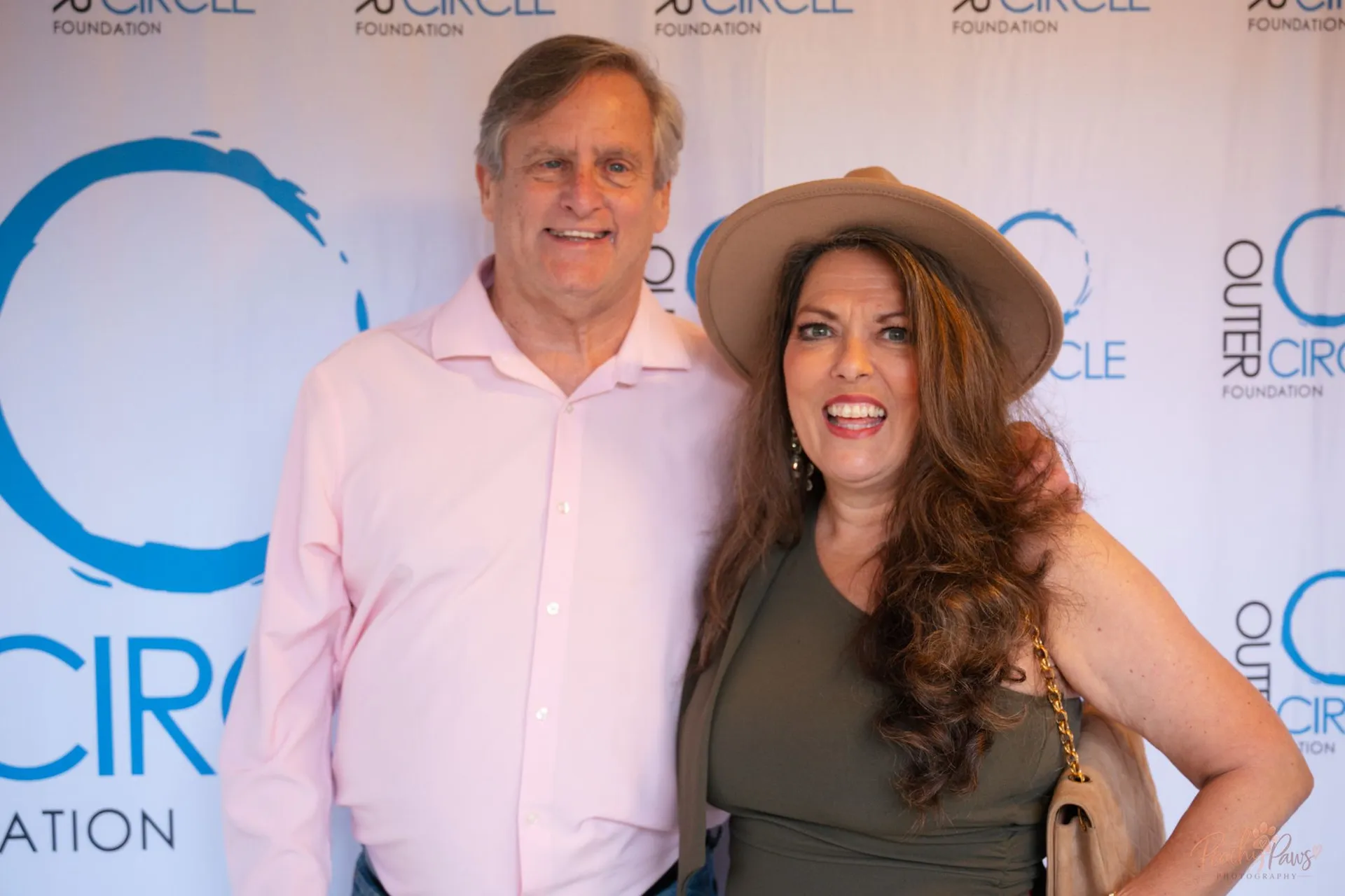 Gala guests smiling together in front of the Outer Circle Foundation backdrop