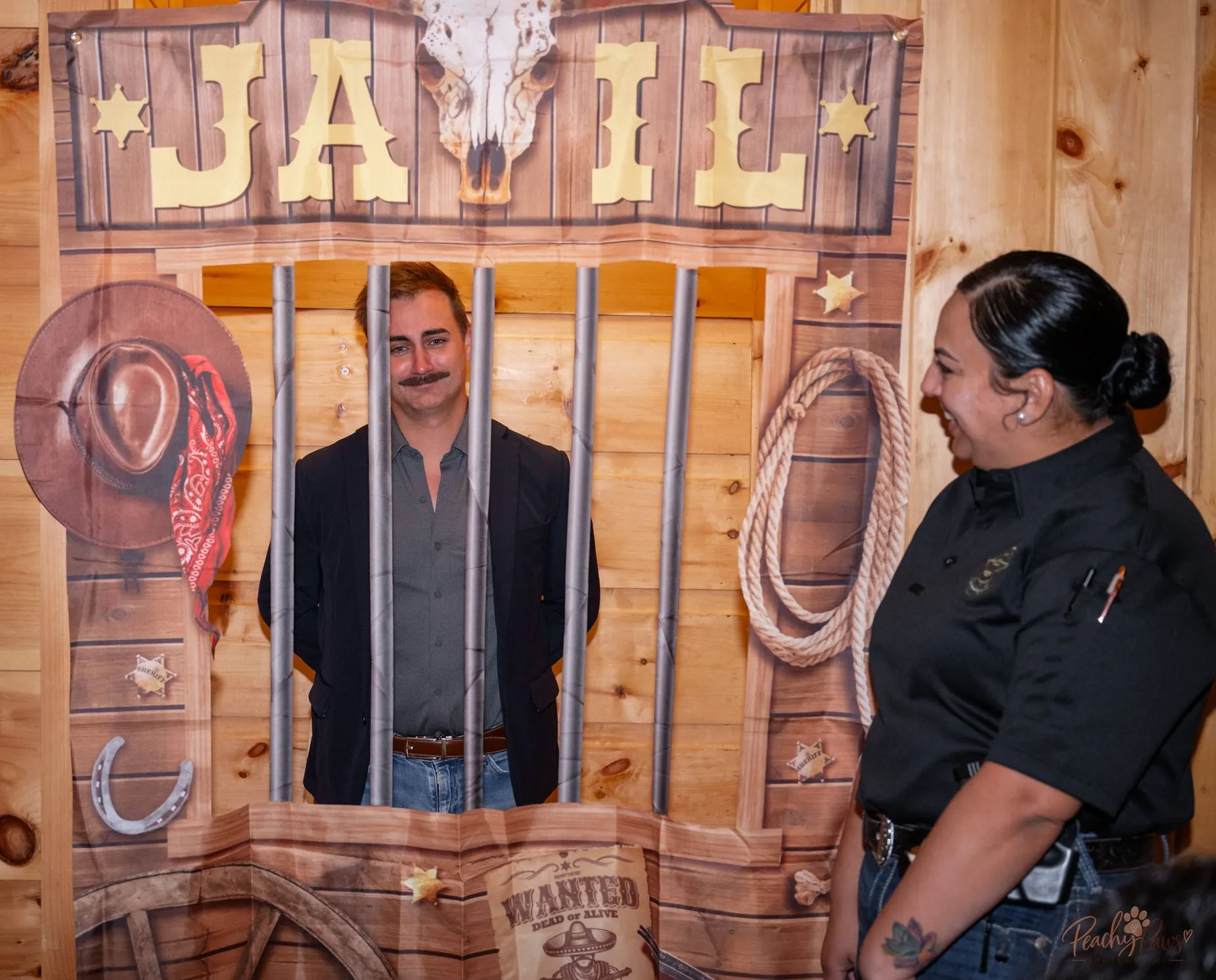 Guests posing with the Western jailhouse prop at the Blue Jean Ball
